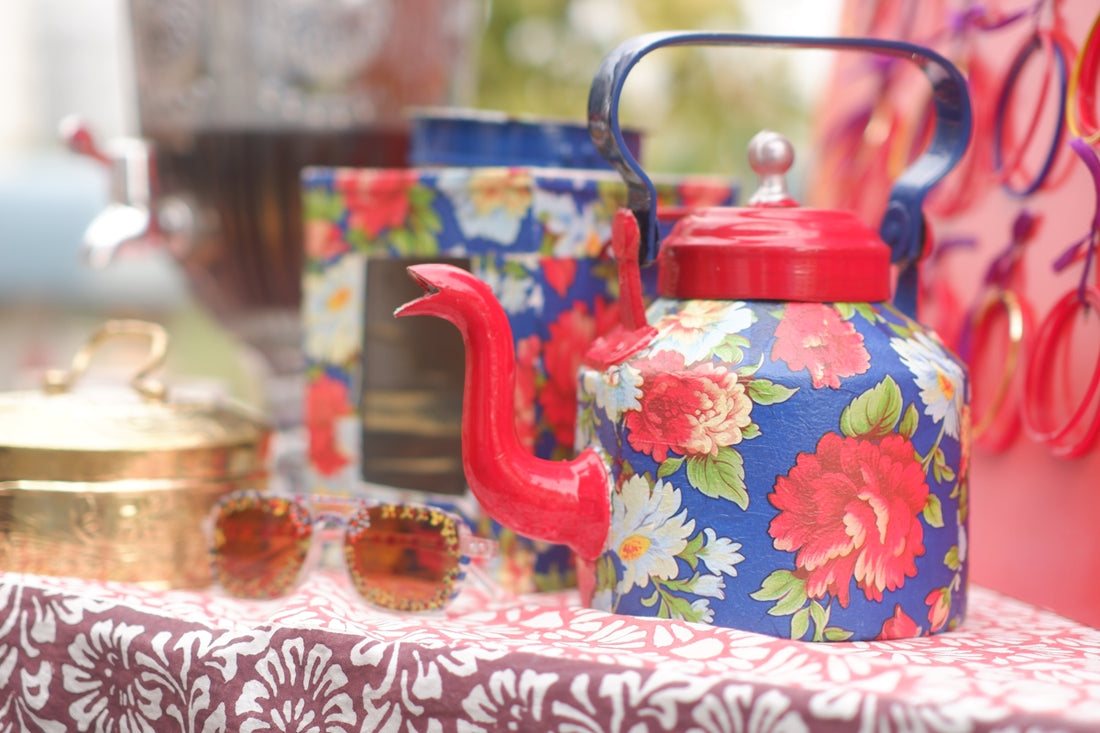 A floral teapot with red lid and handle.